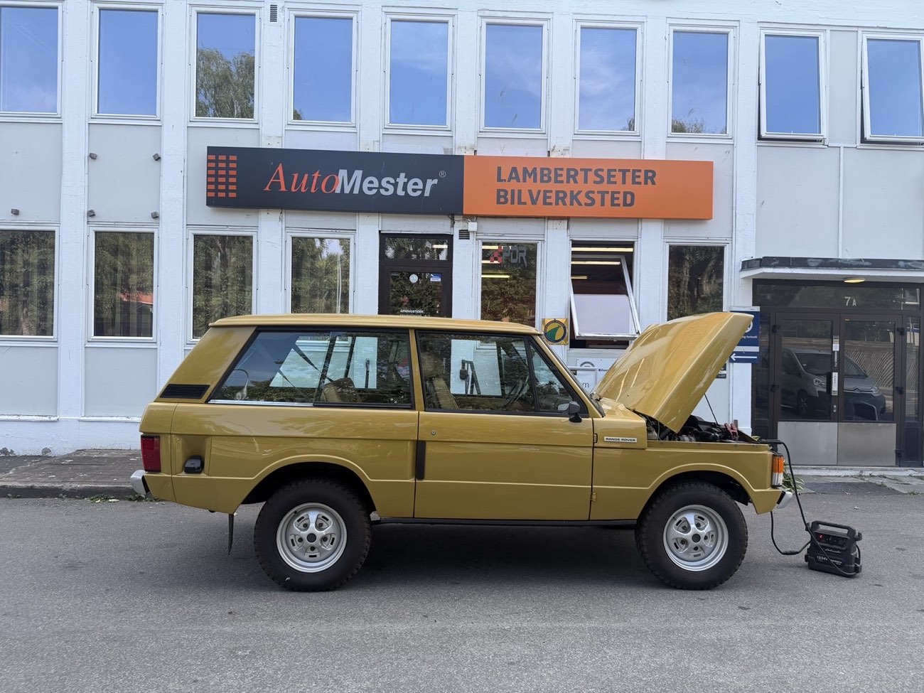 Klassisk gul Range Rover foran Lambertseter Bilverksted, inne til service